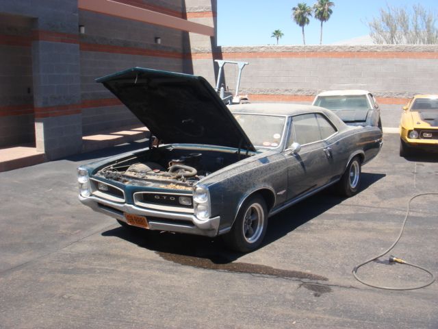 A car with the hood up is parked in a parking lot