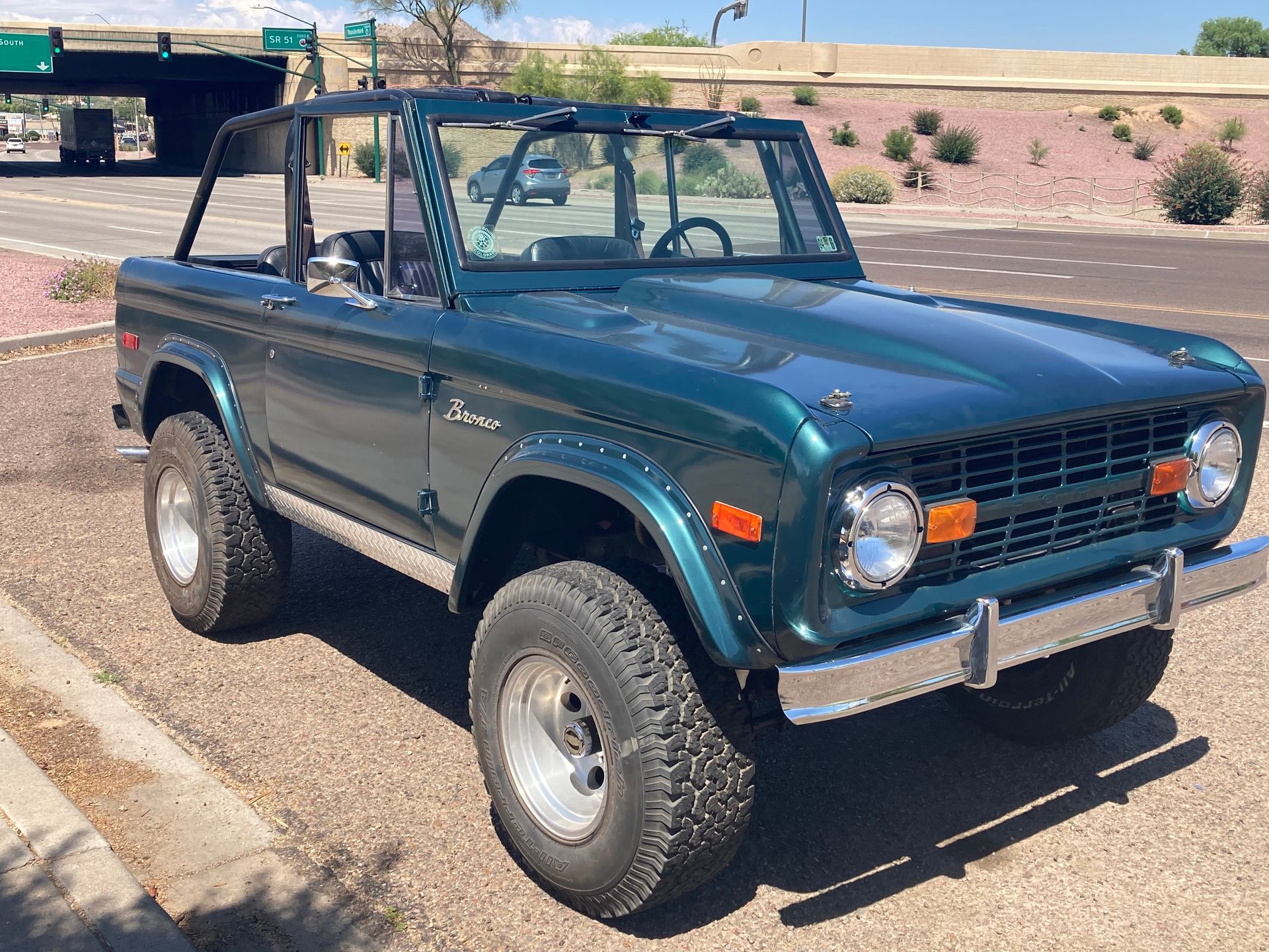A green ford bronco is parked on the side of the road.