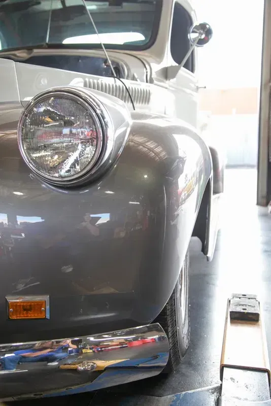 a gray car is parked in a garage next to a white car .