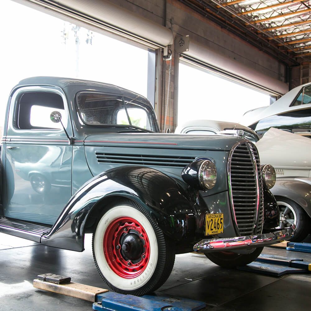 An old truck with a texas license plate is parked in a garage