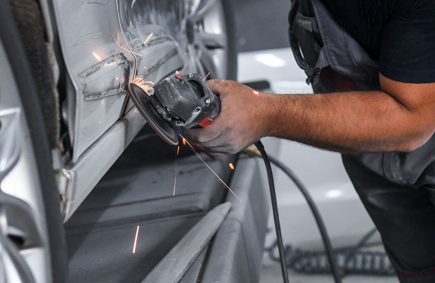 a man is grinding a car door with a grinder .