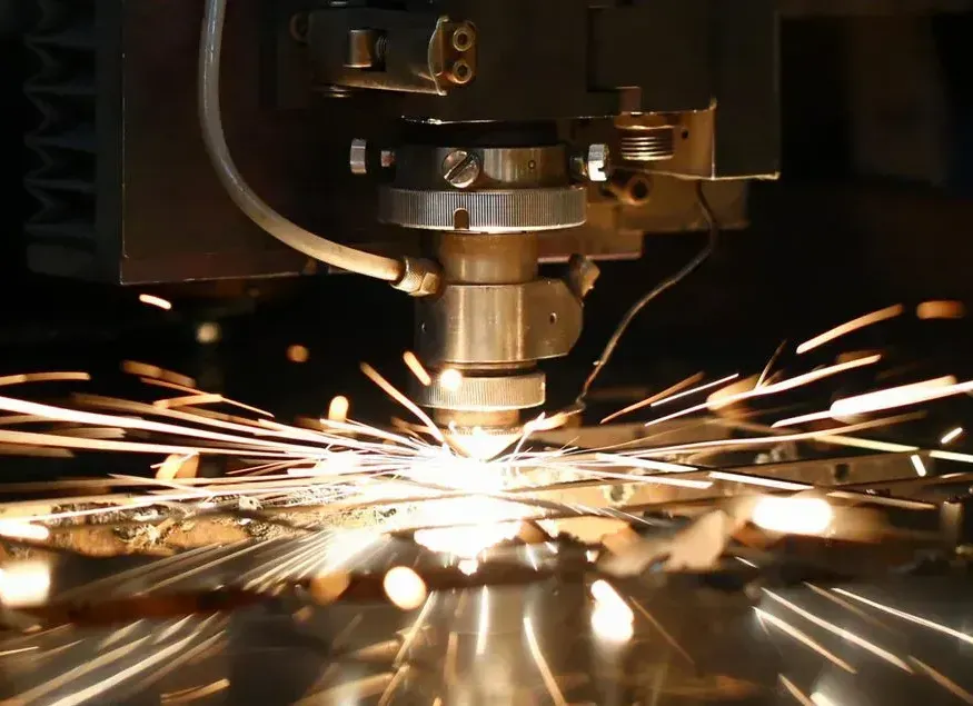 A machine is cutting a piece of metal with sparks coming out of it.