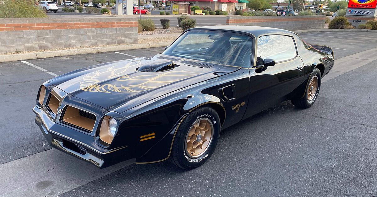 a black pontiac trans am is parked in a parking lot .