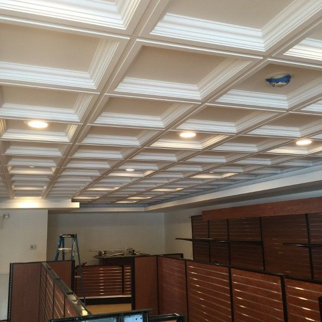 Coffered ceiling with recessed lighting above office cubicles.