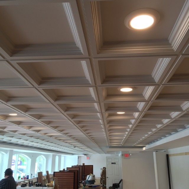 Coffered ceiling with recessed lighting in a commercial space, tan and white colors.