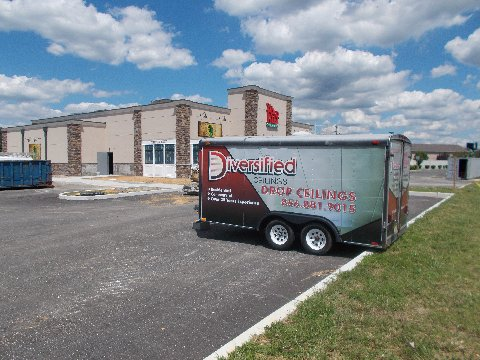 Trailer parked in front of a building under construction, with a cloudy sky in the background.