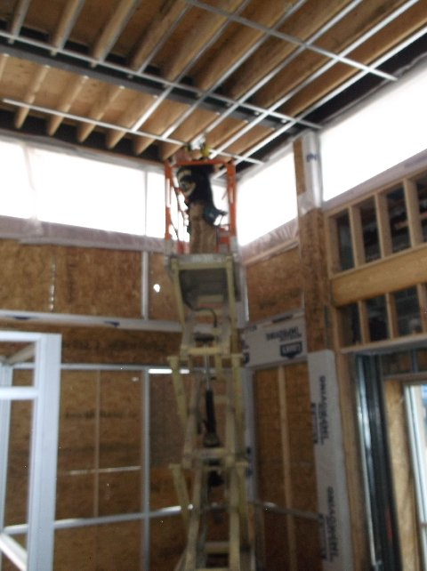 Construction worker on lift, installing ceiling grid in a building under construction.