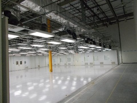 A cleanroom interior with white walls, ceiling lights, and reflective floor.
