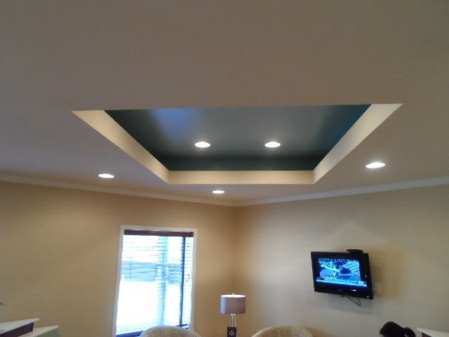 Ceiling with recessed area, teal paint, recessed lighting, crown molding, window, and wall-mounted TV.