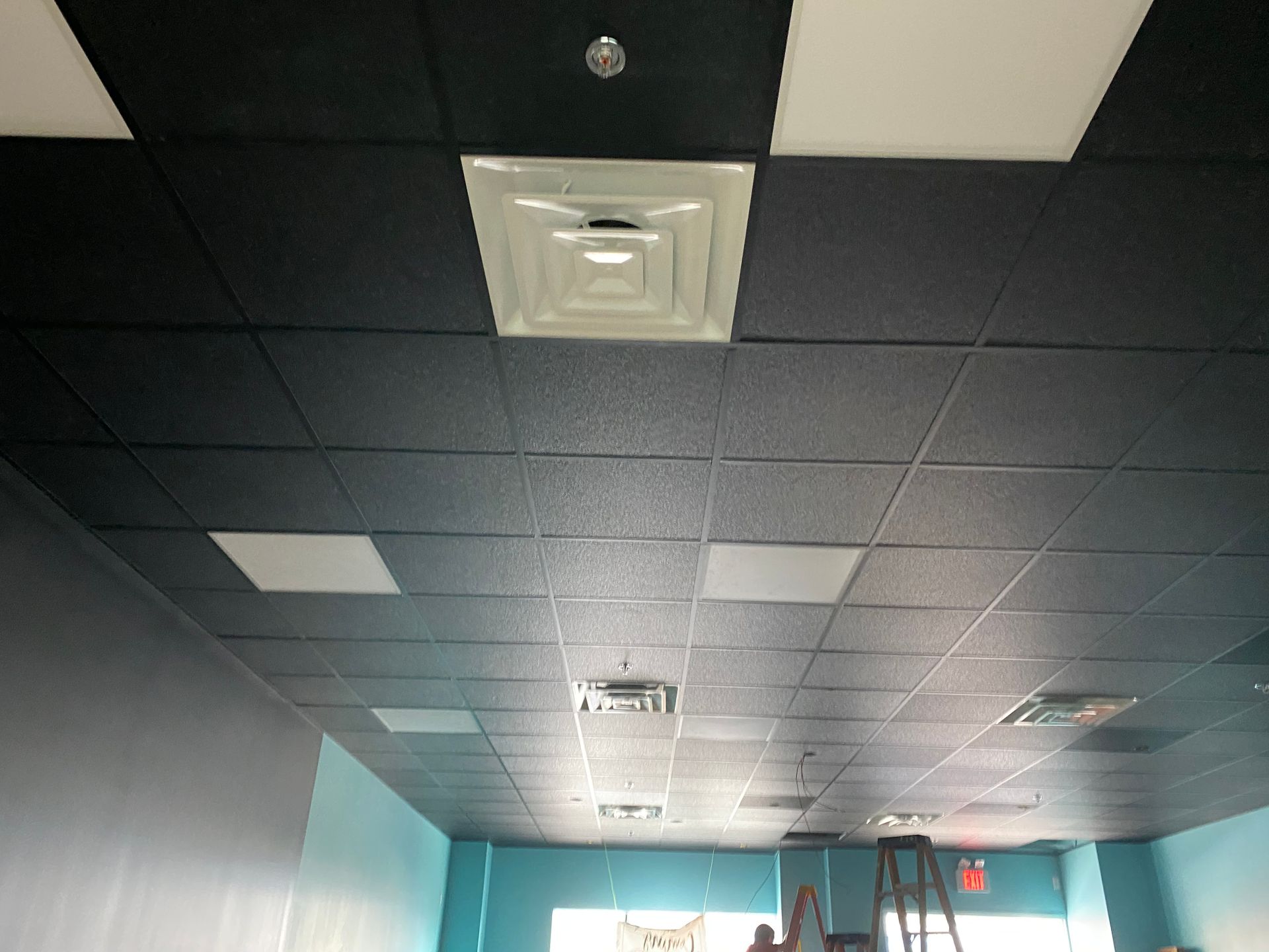 Black and white tiled ceiling with air vents and recessed lights.