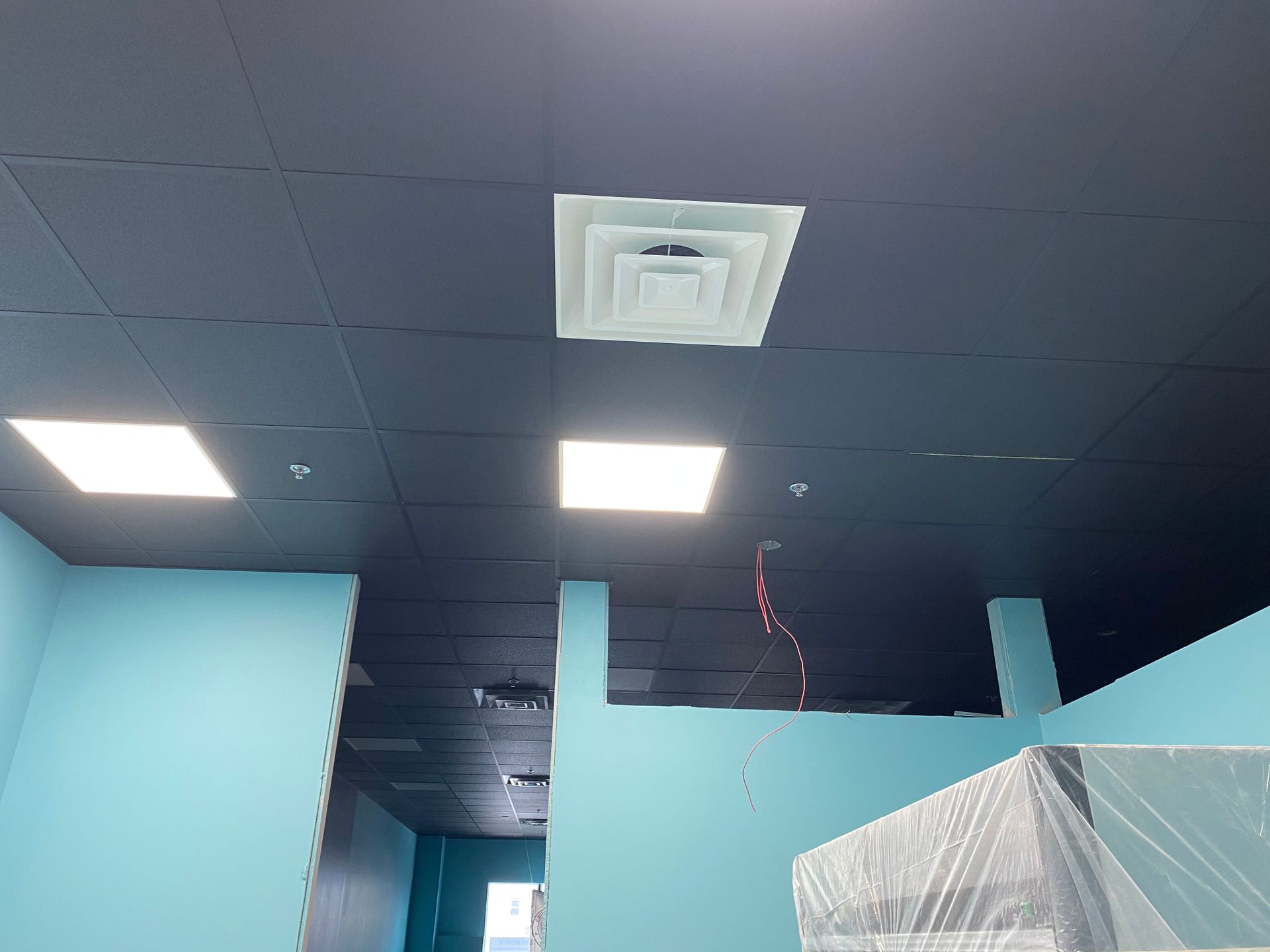 Blue-walled interior with dark blue ceiling, square lights and a vent.