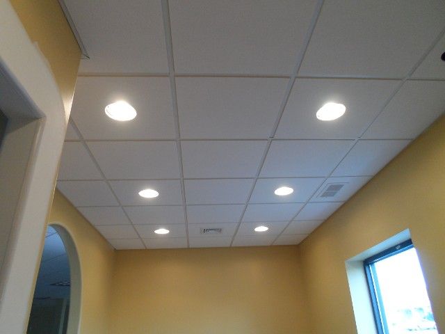 White tiled ceiling with recessed lights in a yellow-walled room.
