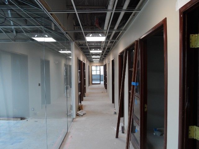 Hallway under construction with doors, exposed ceiling, and lighting.