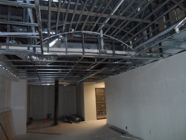 Metal framework for ceiling under construction in a room with white walls and a doorway.