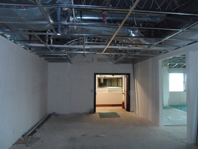 Interior room under construction with exposed ceiling supports, doorways, and unfinished walls.