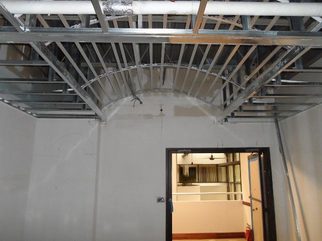 Interior construction with exposed metal ceiling frame and arched detail above a doorway.