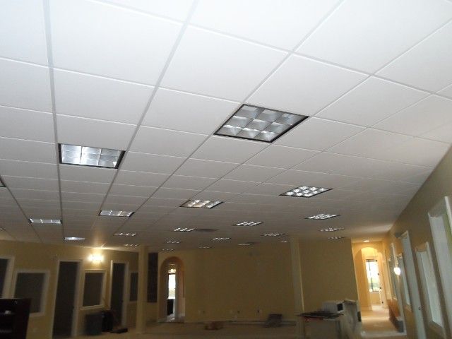 White drop ceiling with recessed fluorescent lights in a large, empty room.