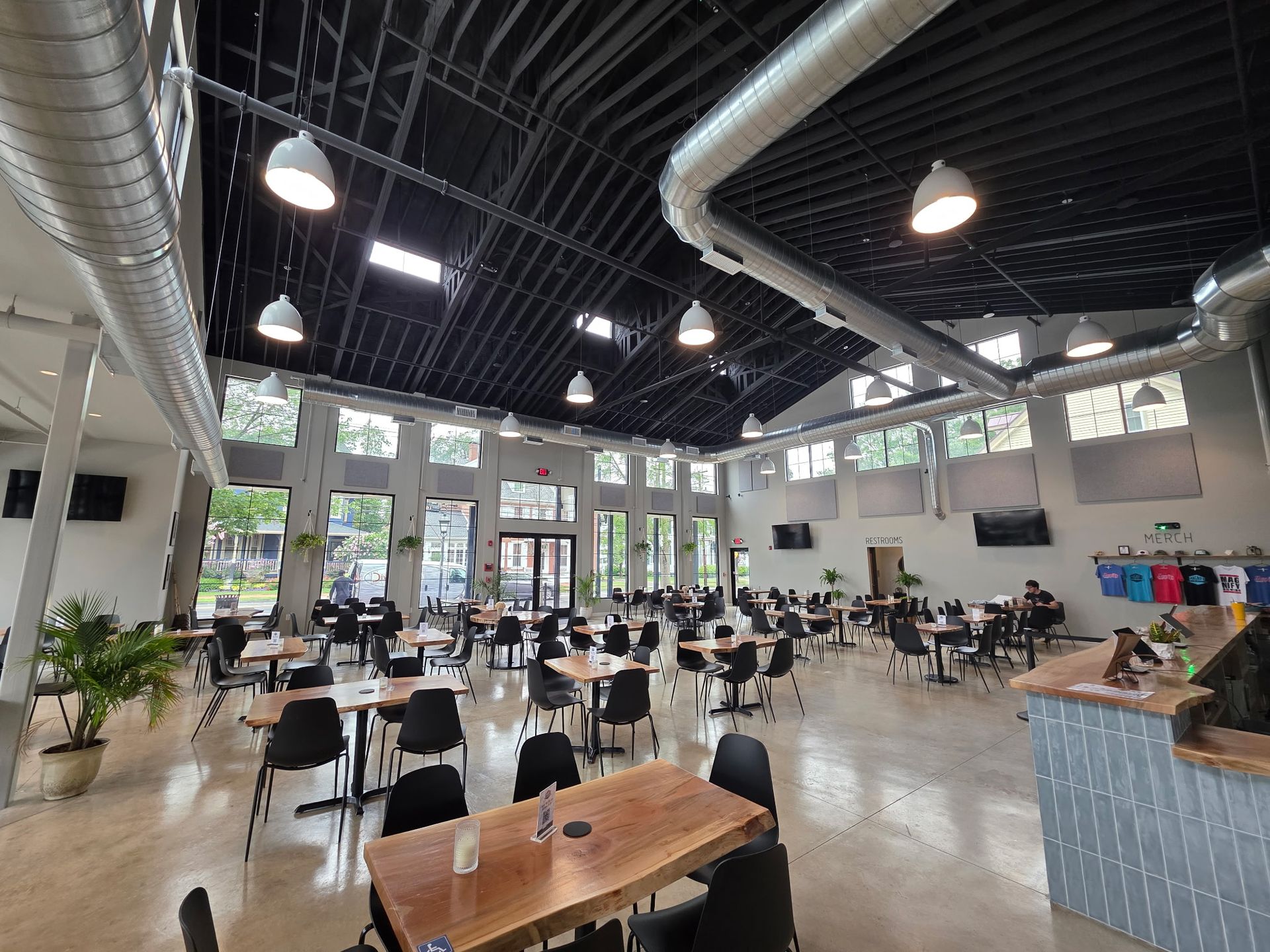 Large, open-plan restaurant interior with tables, chairs, and multiple windows. 