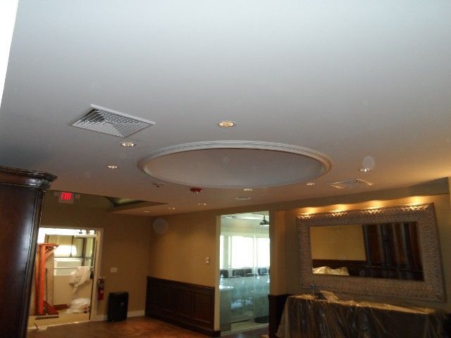 Interior view of a ceiling with a circular design and recessed lighting. A large mirror and doorways are also visible.