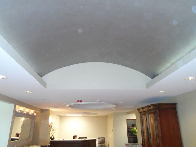 Ceiling with recessed lighting and a curved, arched detail. Off-white and gray colors.
