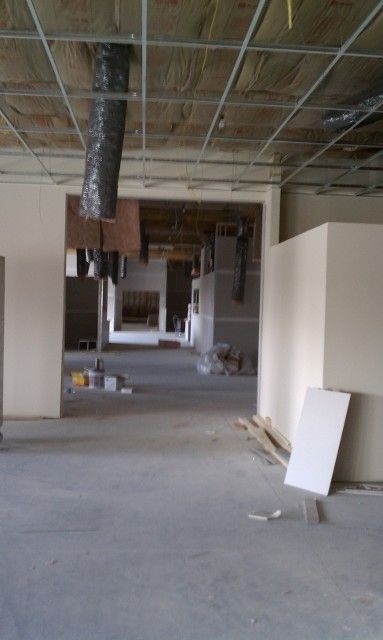 Interior of a building under construction, showing unfinished walls, ceiling framework, and concrete floor.