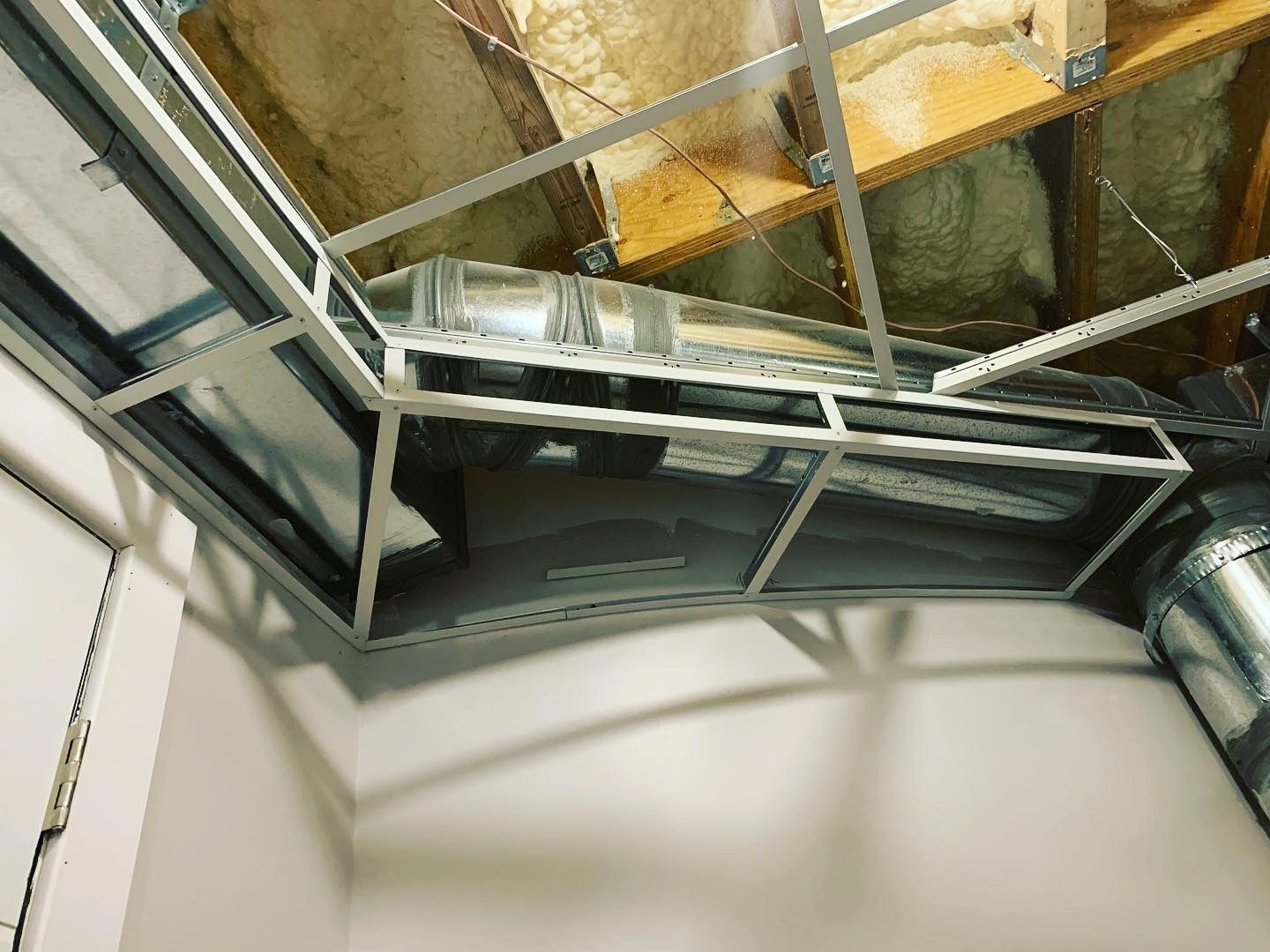 Metal framework and ductwork against an unfinished ceiling, likely a construction or renovation site.