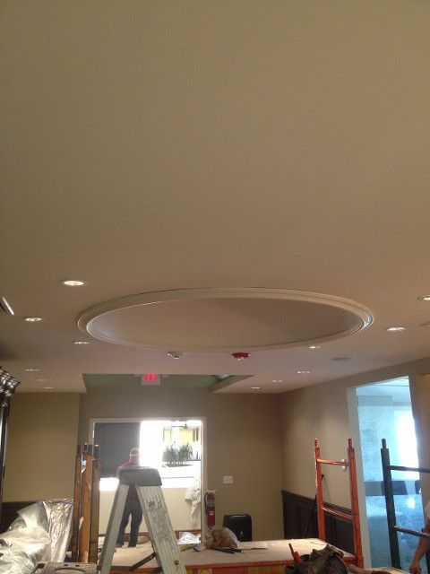 Interior room with an oval ceiling design, lighting, and workers.