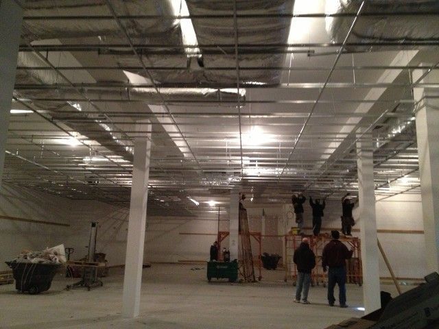 Interior construction site with workers near columns and ceiling framework.