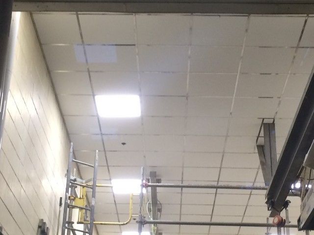 Ceiling with grid pattern and bright overhead lights in an industrial setting.