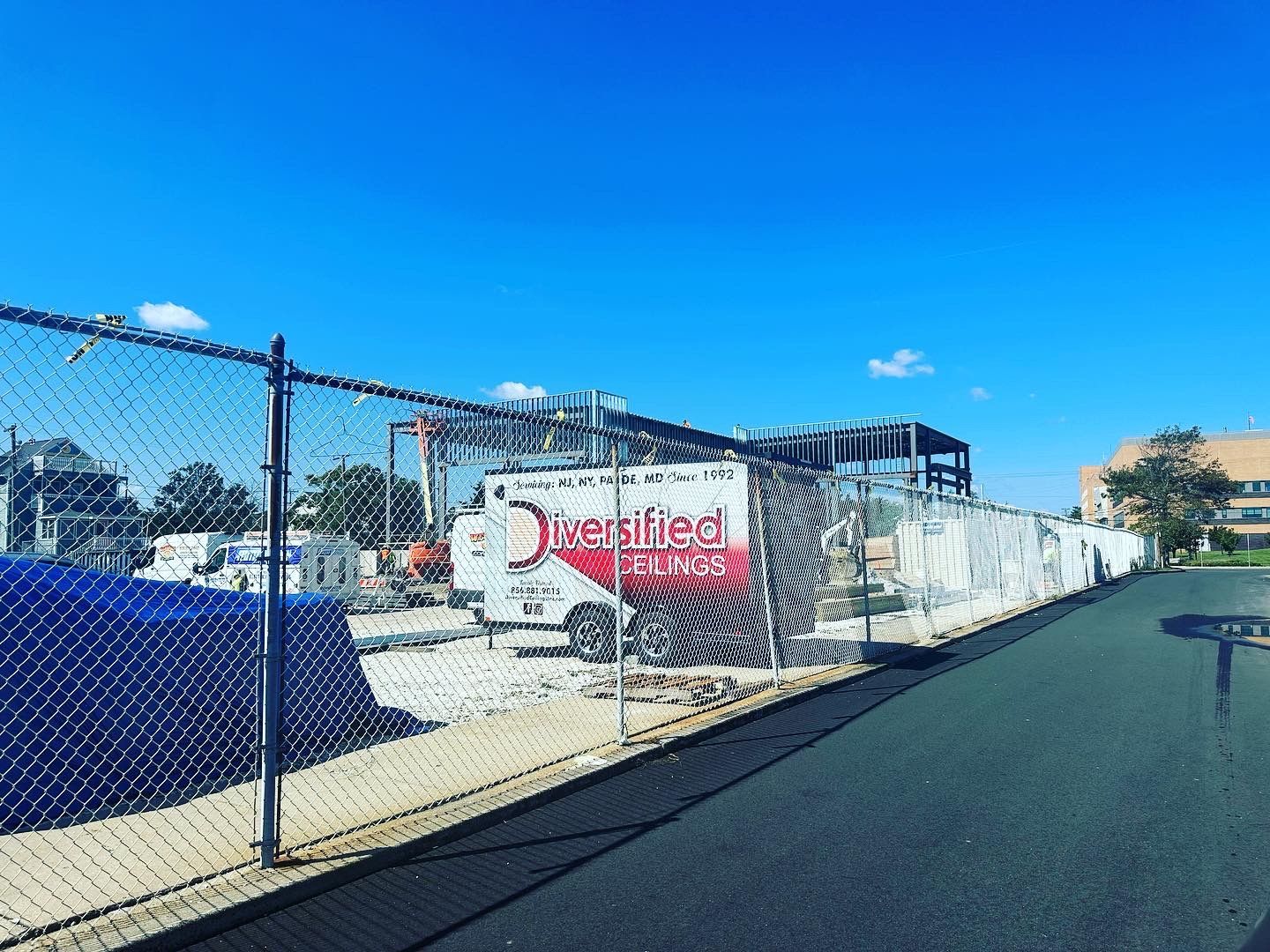Construction site behind a chain-link fence on a sunny day. 