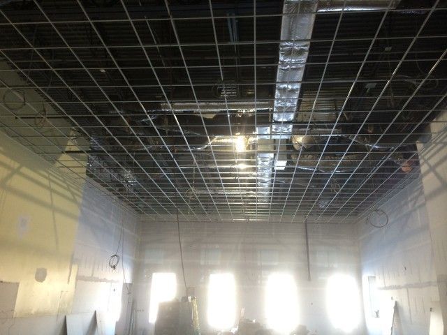 Interior room with exposed ceiling grid, air ducts, and unfinished walls.