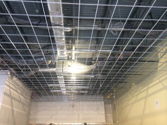 Metal grid ceiling structure, with ductwork visible, in a building under construction.