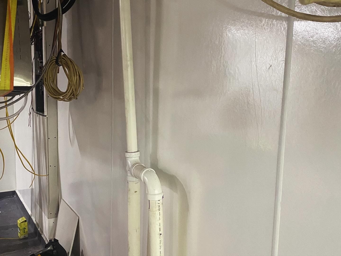 White pipes and wires against a white wall in an indoor setting.