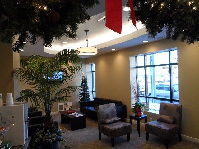 Cozy waiting room with black couch, patterned chairs, large windows, and Christmas decorations.
