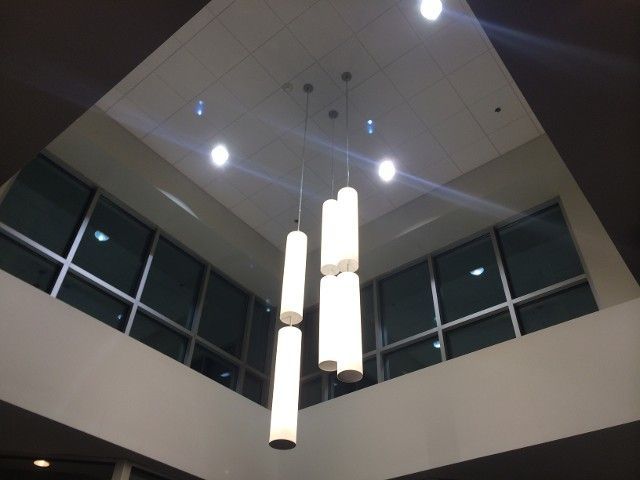 Modern interior with a ceiling cutout, pendant lights, and large windows.