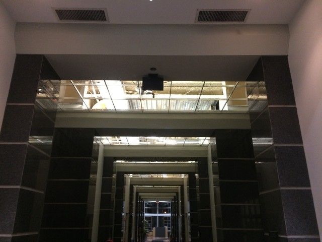 Hallway with mirrored pillars and recessed ceiling lights, perspective view.