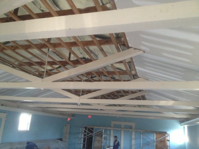 Interior construction site with exposed ceiling beams and drywall installation.