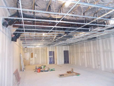 Construction of an interior space. Metal framework for ceiling and walls. Drywall and insulation visible.
