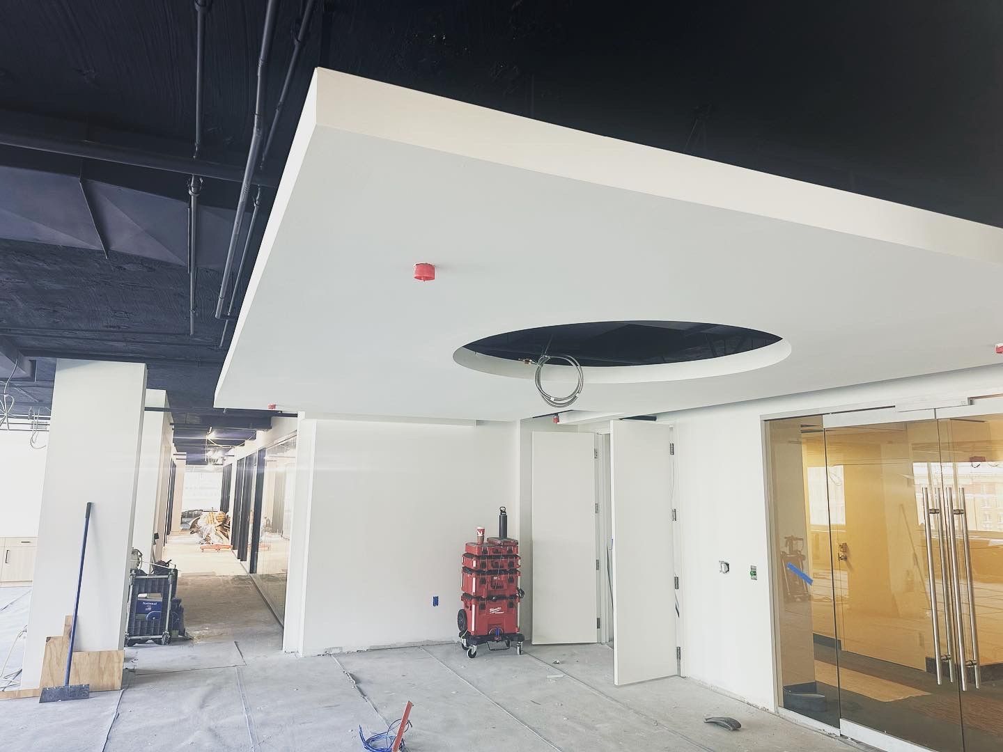 Interior view of unfinished construction site with white walls, exposed ceiling, and a circular ceiling design.