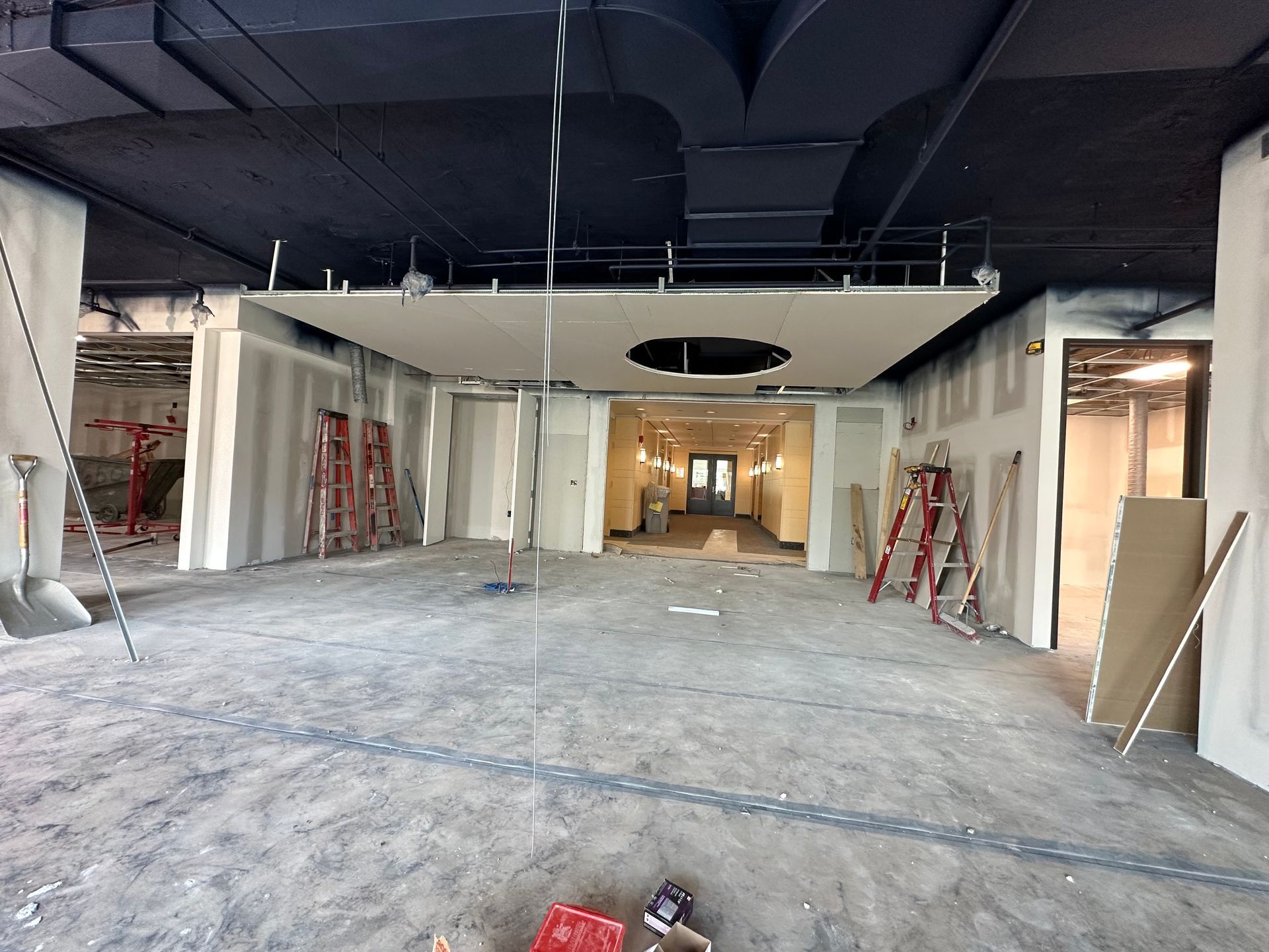 Construction site interior with exposed ceiling, drywall, and unfinished concrete floor.