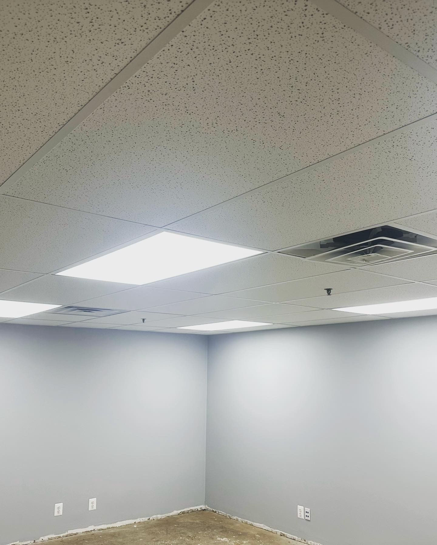 An empty room with gray walls and a textured ceiling with recessed lighting.