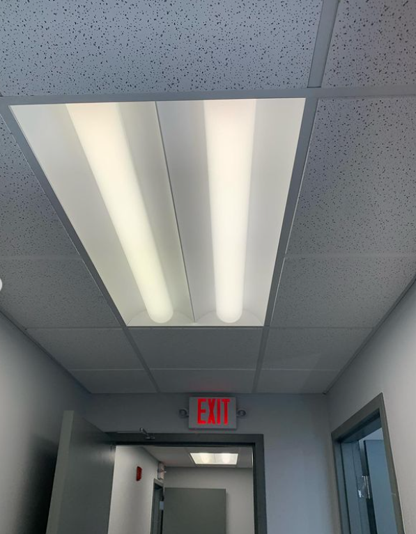 Hallway ceiling with fluorescent lights and an exit sign.