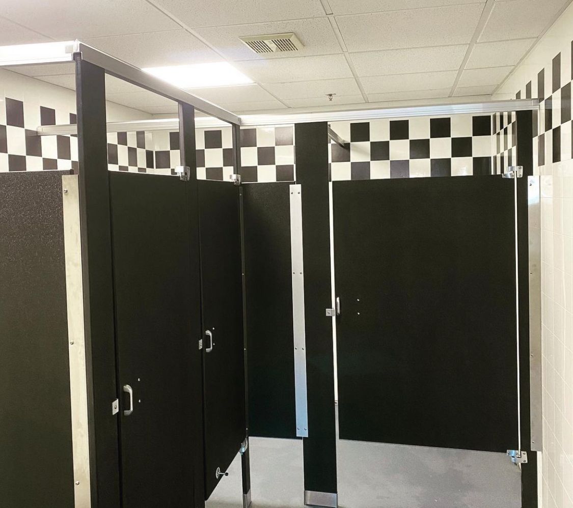 Black restroom stalls with checkerboard wall tiles.