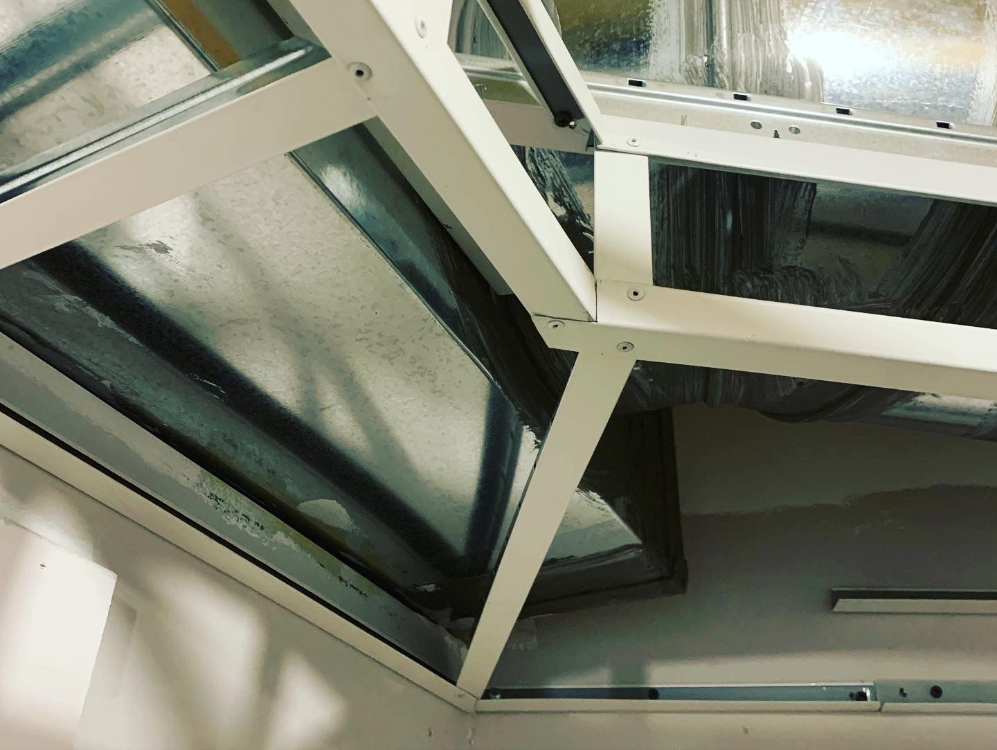 White metal framing supporting exposed ductwork in a corner.