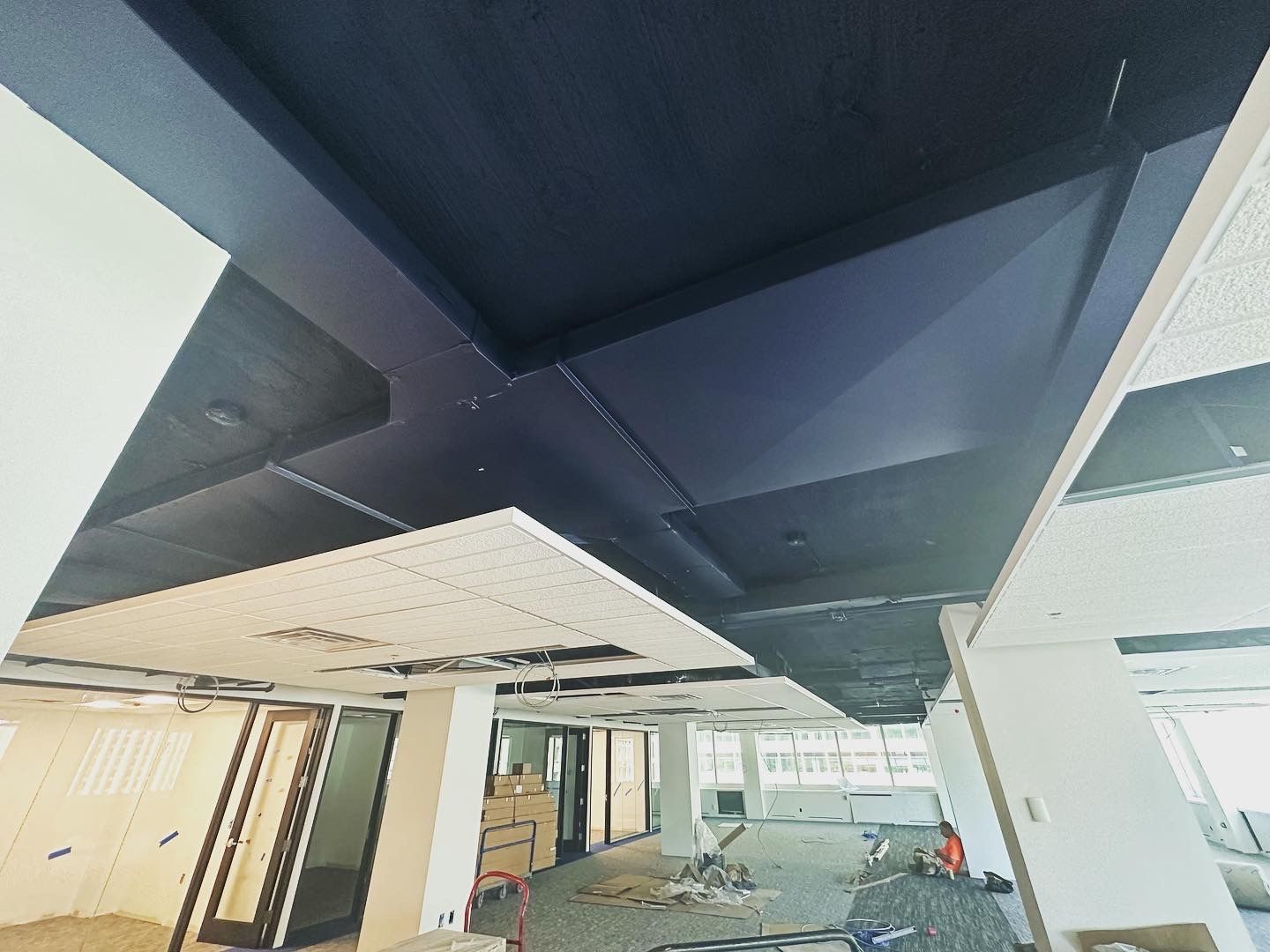 Construction site interior with a black painted ceiling and exposed white panels.