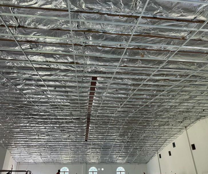 Ceiling under construction with foil insulation and metal grid framework.