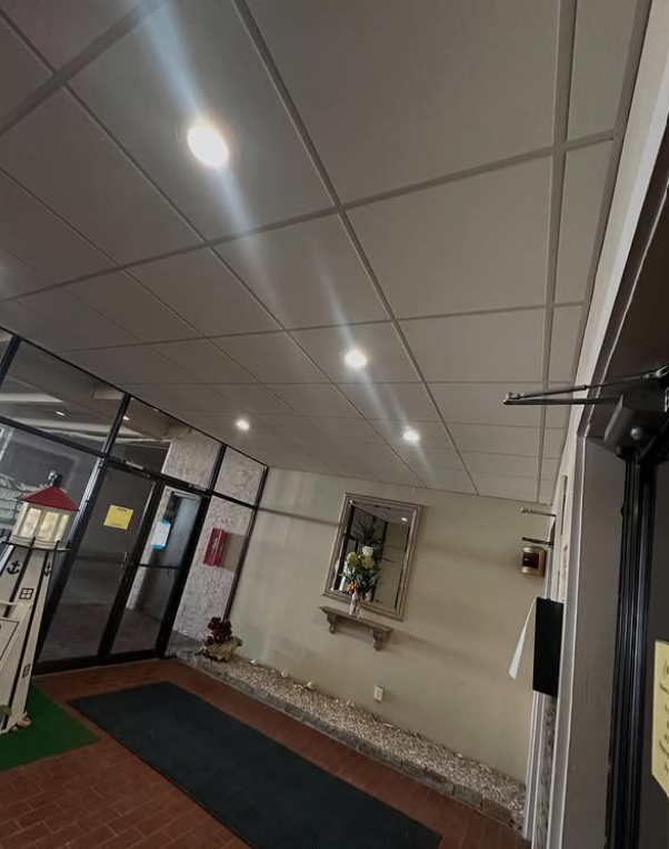Hallway with recessed ceiling lights, mirrored wall décor, and a brick floor.