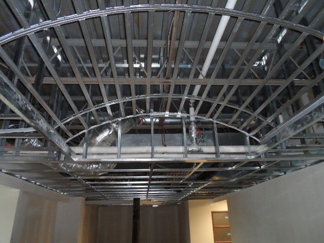 Steel framework of a curved ceiling section under construction, with ductwork visible.
