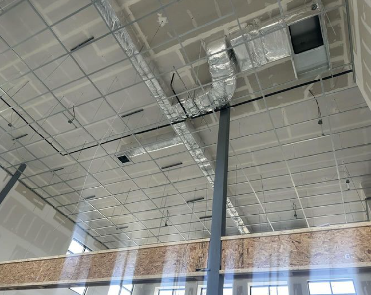 Visible are drywall ceilings, ductwork, metal support beams, and exposed studs.