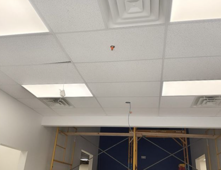 White ceiling with recessed lighting and a sprinkler head. Scaffolding is visible below.